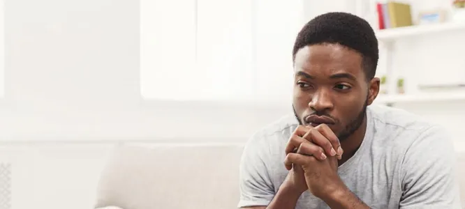 A young man sitting on a sofa, deep in thought