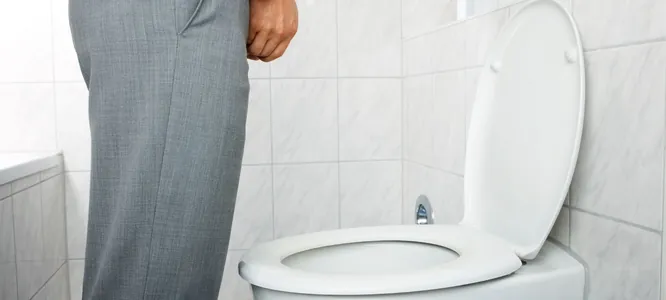 A man standing at a toilet