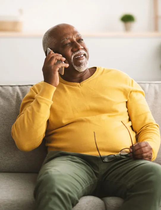 An older man at home on the phone, smiling